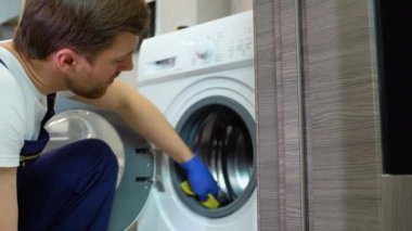 Çamaşır makinesinin kirli mühürlerini temizleyen işçiler, yakın plan..