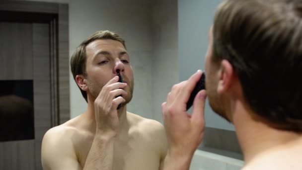 Schöner Junger Mann Entfernt Mit Trimmer Haare Von Der Nase — Stockvideo