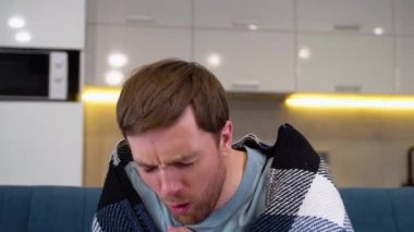 Sick man holding his chest in pain while coughing in the living room.