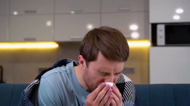 一个穿睡衣的男人吹着她的鼻子 患感冒的人的概念 — 图库视频影像