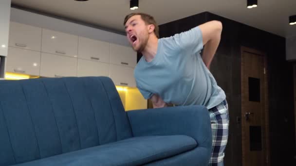 Junger Mann Leidet Unter Rückenschmerzen Beim Anheben Des Sofas Wohnzimmer — Stockvideo