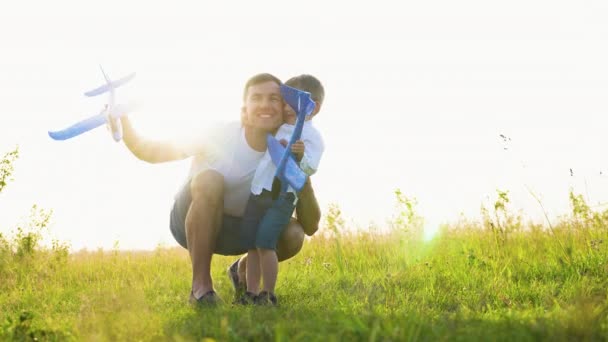 快乐的家庭 爸爸在日落时一起在公园里玩飞机 团队合作的爸爸 飞行员 在阳光下手握玩具飞机 — 图库视频影像