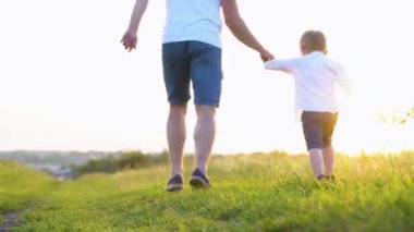 Mutlu baba ve küçük oğlu parkta birlikte koşuyorlar. Mutlu aile takımı. Aile oyunu. Baba oğul eğlence koşusu.