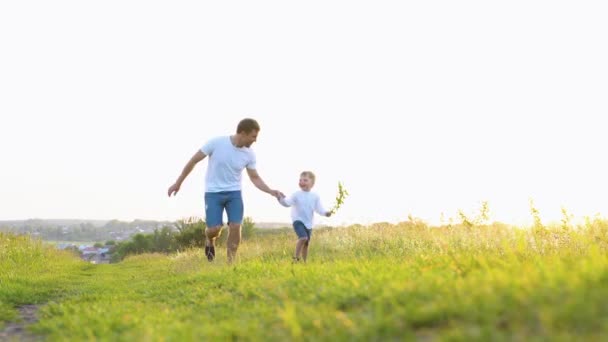快乐的父亲和小儿子在田野里一起在阳光下奔跑 快乐的家庭团队家庭游戏 — 图库视频影像