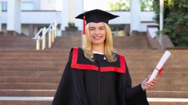 Havan topu diploması olan tatmin olmuş bir öğrencinin portresi. Mutlu genç sarışın mezun kadın ayakta kameraya bakıyor.