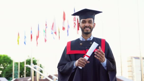 陽気なインディアン男で卒業式の衣装ショー彼の卒業証書と笑顔でカメラ — ストック動画