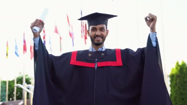在大学校园里 身穿斗篷戴帽的快乐的印度研究生 在毕业典礼上庆祝并做出获胜的姿态 — 图库视频影像