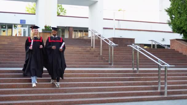 Щасливі Багаторасові Випускники Йдуть Сходами Університеті Мантії Дипломами Руці — стокове відео