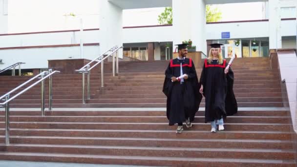 Dos Estudiantes Universitarios Multirraciales Batas Graduación Tableros Mortero Caminando Campus — Vídeos de Stock