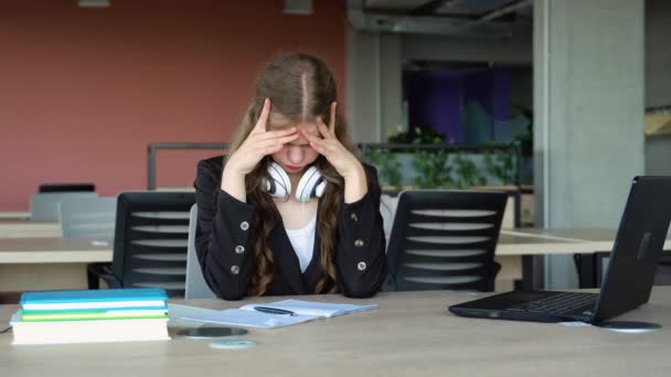 在大学图书馆里 沮丧的女学生坐在书桌前 手里拿着一堆学习书 — 图库视频影像