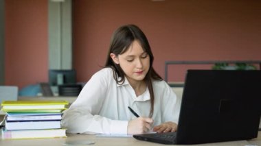 Sınıfta dizüstü bilgisayar kullanan odaklanmış kız, çekici kız öğrenci öğrenme dili, çevrimiçi webinar izleme, ses kursu dinleme, e-öğrenme konsepti.