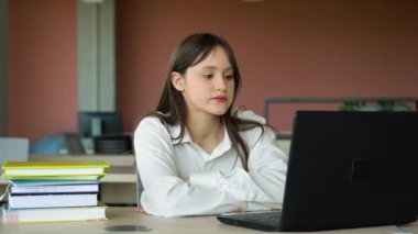 Sınıfta dizüstü bilgisayar kullanan odaklanmış kız, çekici kız öğrenci öğrenme dili, çevrimiçi webinar izleme, ses kursu dinleme, e-öğrenme konsepti.