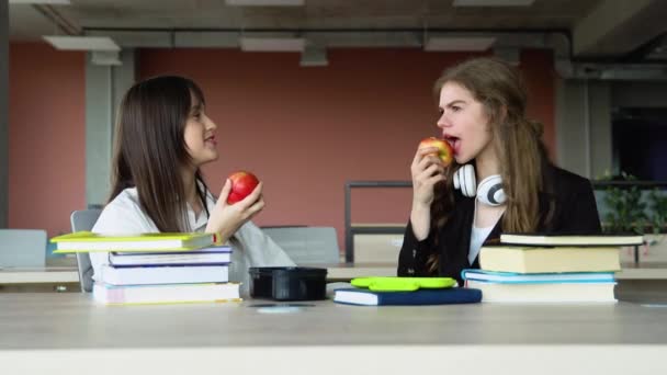 休みの日にりんごを持っているフレンドリーな学生 学校で昼休みに二人の女の子 — ストック動画