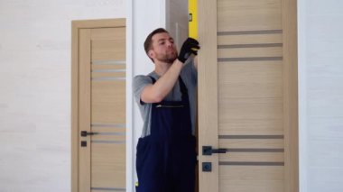 Erkek marangoz iç ahşap kapıyı düzgünce yerleştiriyor.