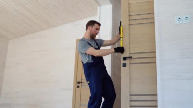 Erkek marangoz iç ahşap kapıyı düzgünce yerleştiriyor..