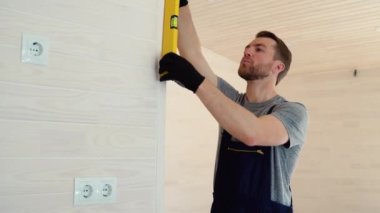 İnşaatçı ahşap prefabrik evdeki duvarın dikey sapmasını ölçüyor. Kabarcık düzeyi cetvel görünümü, ölçümü ve seviyelendirme kavramını kapat