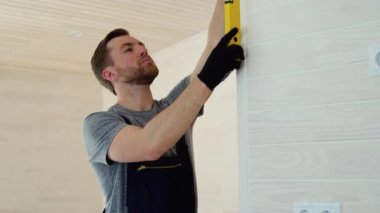 İnşaatçı ahşap prefabrik evdeki duvarın dikey sapmasını ölçüyor. Kabarcık düzeyi cetvel görünümü, ölçümü ve seviyelendirme kavramını kapat