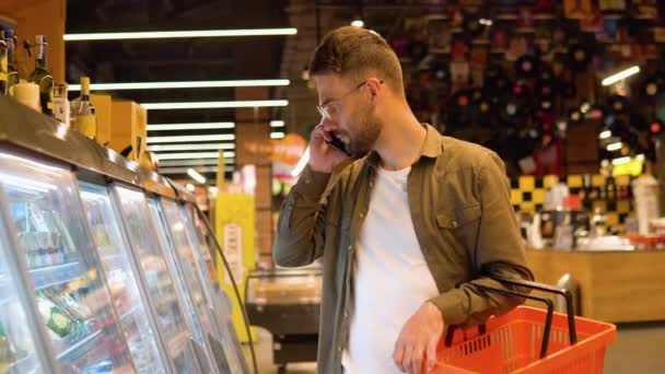 Mladý Muž Brýlemi Supermarketu Nakupuje Vybírá Produkty Telefonuje Konzultuje Svou — Stock video