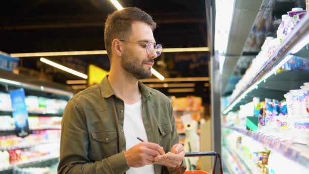 スーパー マーケットの通路で彼のメモ帳で書いているその男 — ストック動画