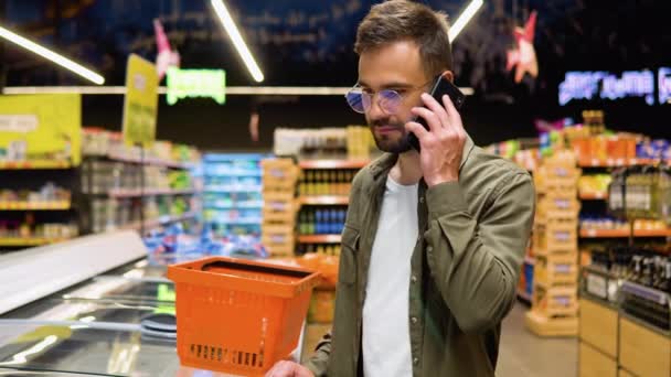 Junger Mann Mit Brille Kauft Supermarkt Ein Wählt Produkte Aus — Stockvideo