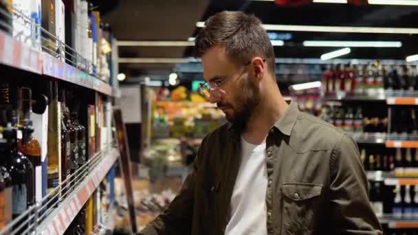 Ein Junger Mann Einem Supermarkt Wählt Alkohol Der Weinabteilung — Stockvideo