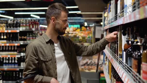 Молодой Человек Супермаркете Выбирает Алкоголь Винном Отделе — стоковое видео