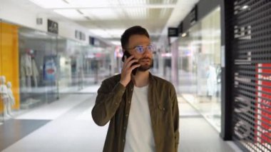 Alışveriş merkezinde yürüyen yakışıklı genç adam..