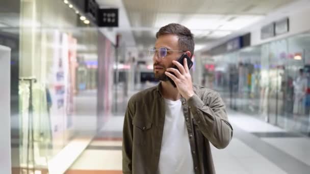 Przystojny Młodzieniec Rozmawiający Przez Telefon Komórkowy Uśmiechnięty Podczas Spaceru Centrum — Wideo stockowe
