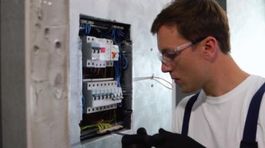 Profesyonel elektrikçi daireye elektrik kuruyor. Elektrikçi elektrik kutusunu tamir ediyor ve koridorda tornavida kullanıyor..