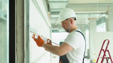 Alçıpan işçisi ya da alçı işçisi ofis duvarının dikişlerini kapatıyor..