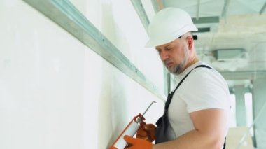 Alçıpan işçisi ya da alçı işçisi ofis duvarının dikişlerini kapatıyor..