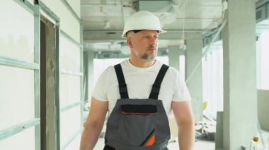 40 'ların kendine güvenen mühendis mimarı bir inşaat sahasında yürüyor. Modern şantiyede inşaat işçisi..