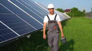 Mühendis ile güneş çiftliği sistemin işleyişini kontrol etmek için yürür, dünyanın enerjisini korumak için alternatif enerji, temiz enerji üretimi için fotovoltaik modül fikri.