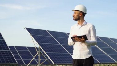 Mühendis güneş panellerini test etmek için tablet kullanıyor. Yüksek güneş enerjisi kullanımı.