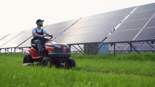 Trabajador Hombre Cortando Hierba Con Cortacésped Estación Paneles Solares — Vídeo de stock