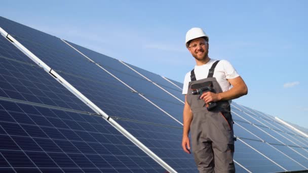 太陽電池パネルの近くのドリルを持つ技術者の肖像 太陽光発電所の運転 維持管理 — ストック動画