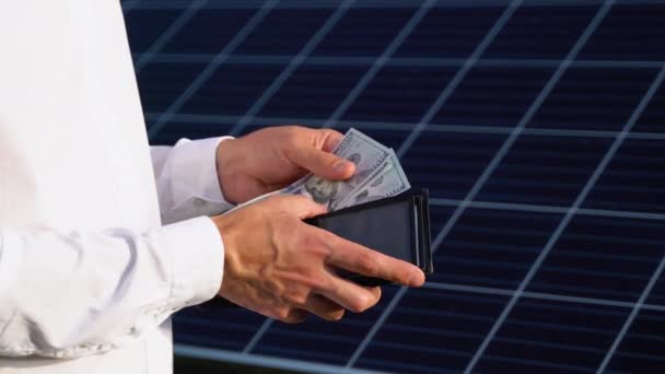 太陽光発電パネルを背景にドル紙幣を保持する技術者 — ストック動画