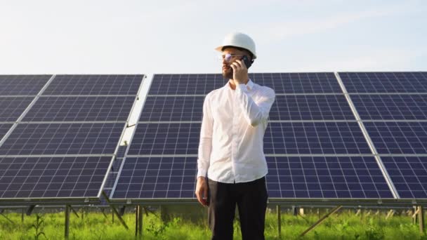 自信的男人戴着安全帽 拿着手机 打电话 从事太阳能电池板概念工作的工程师 工人或建筑师 — 图库视频影像