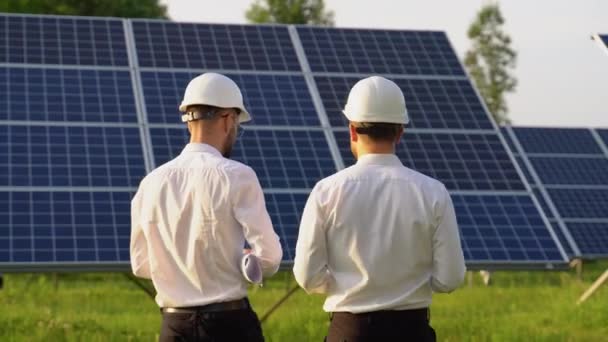 两名工程师行走和检查光伏太阳能电池板 替代能源的概念及其服务 — 图库视频影像
