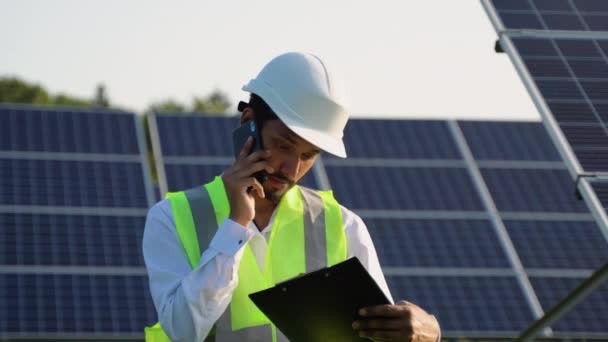 印度戴头盔的工程师在谈论手机 从太阳能发电厂建筑工地的治理工作中获得建议 协定概念 — 图库视频影像