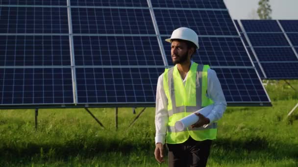 保護ワークウェアウォーキングと太陽光発電パネルを調べるインドのエンジニアと太陽光発電所 — ストック動画