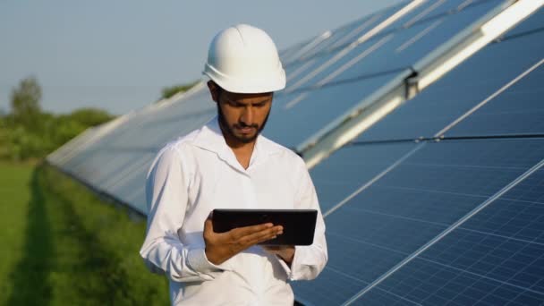 年轻的印度工程师站在蓝天明亮的太阳能电池板旁边 研究平板电脑 可再生能源 绿色能源和清洁能源 复制空间 工作上的工人 印度技能A — 图库视频影像