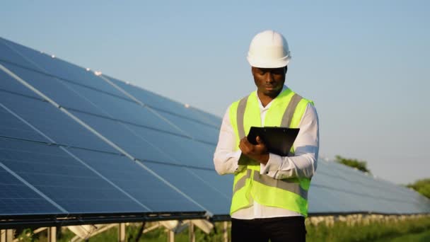 Trabajador Mantenimiento Negro Joven Mirando Portapapeles Cerca Paneles Solares — Vídeos de Stock