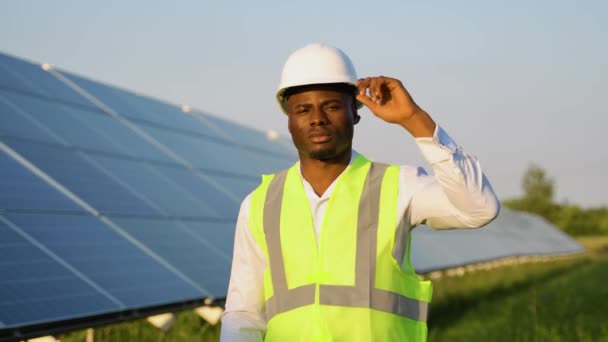 在太阳能电池板附近 非洲工程师头戴头盔的肖像 太阳能发电厂的运行和维护 — 图库视频影像