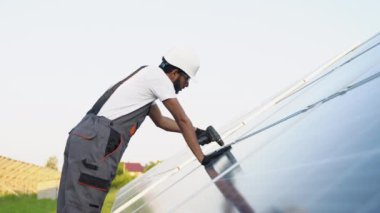 Hint mühendis güneş panellerini koruyor. Ekolojik güneş çiftliği inşaatında çalışan bir teknisyen. Yenilenebilir temiz enerji teknolojisi kavramı.