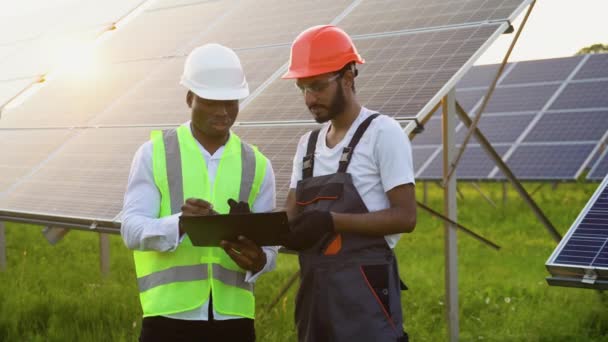 两名亚洲男性工程师目前正在计划在可再生的太阳能发电厂安装太阳能电池板 工程师小组谈在农村地区安装太阳能电池 — 图库视频影像