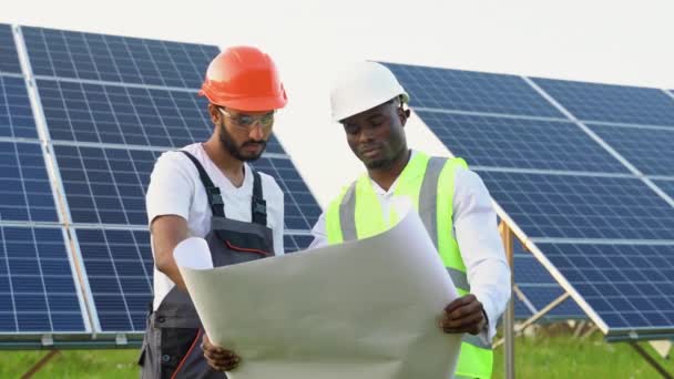 年轻男子和印度技术人员站在那里 计划安装太阳能电池板 关于太阳系安装 可再生能源替代概念的产业工人讨论 — 图库视频影像