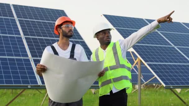 年轻的非洲工程师和印度技术人员站在那里 计划安装太阳能电池板 讨论太阳系安装的产业工人 — 图库视频影像
