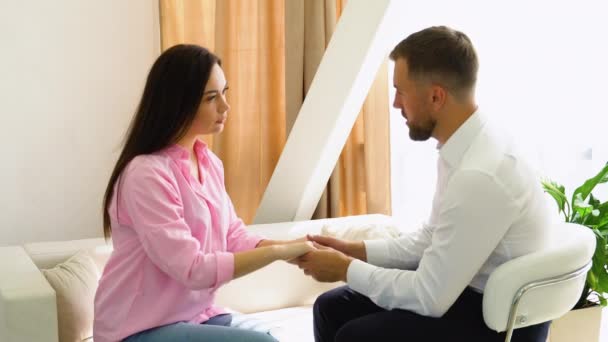 男性心理学者は セラピーセッション中に患者を慰めながら女性の手に手を置く — ストック動画