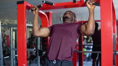 Spor kıyafetli genç Afrikalı Amerikalı bir adam spor salonunda antrenman yaparken terliyor..